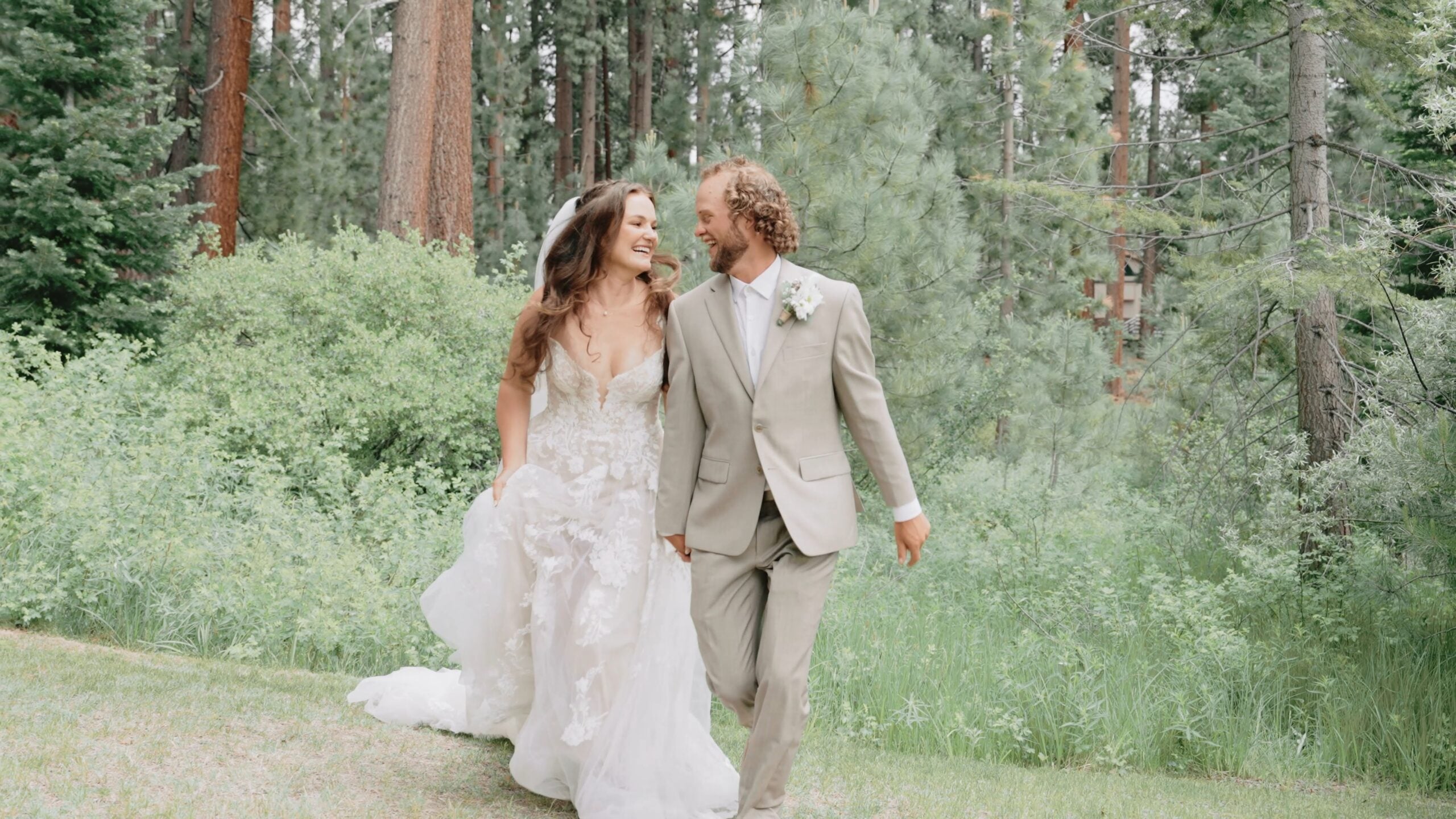 Newlyweds walking among tall pine trees