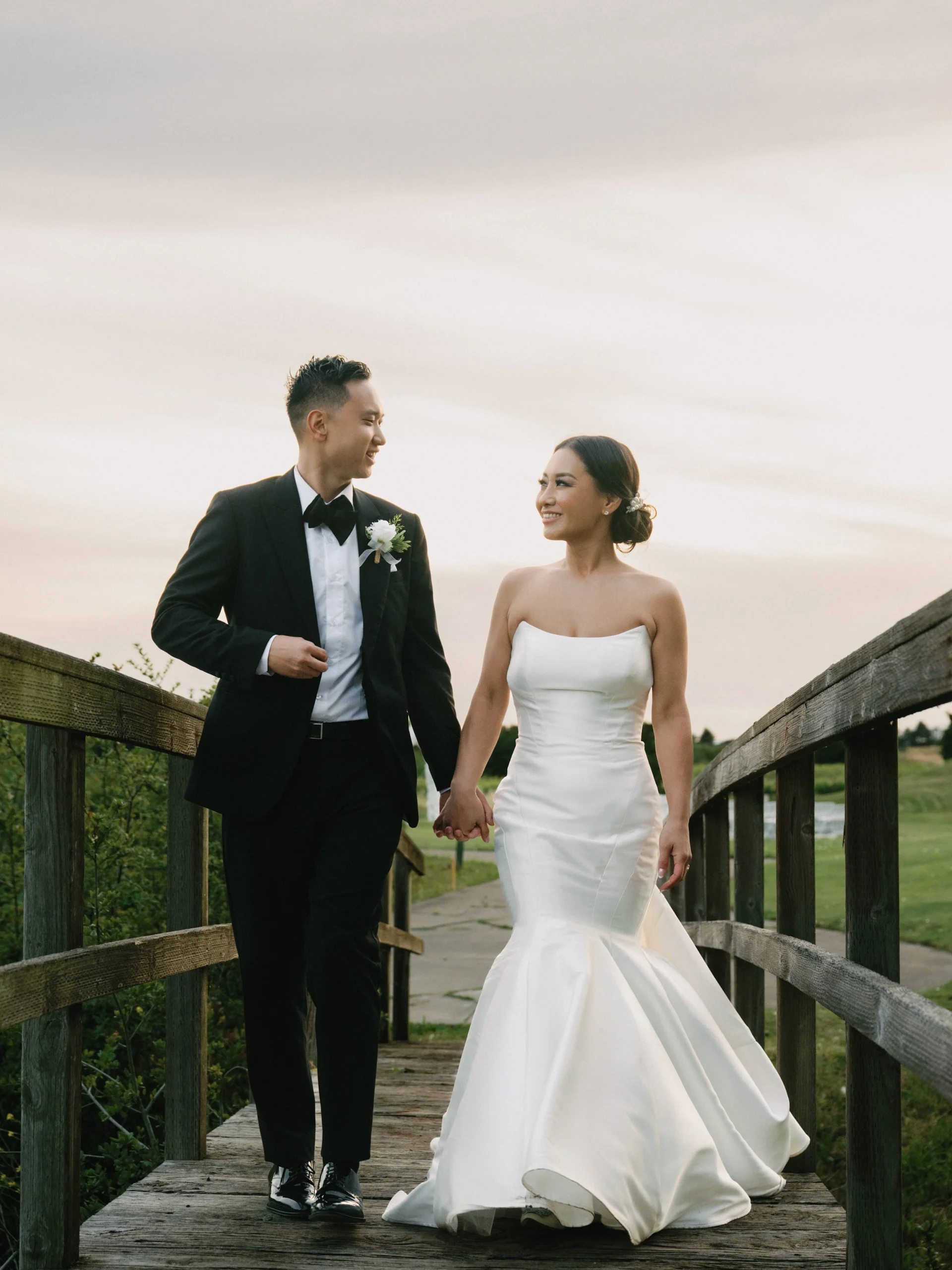 Newlyweds walking hand in hand on a wooden footbridge