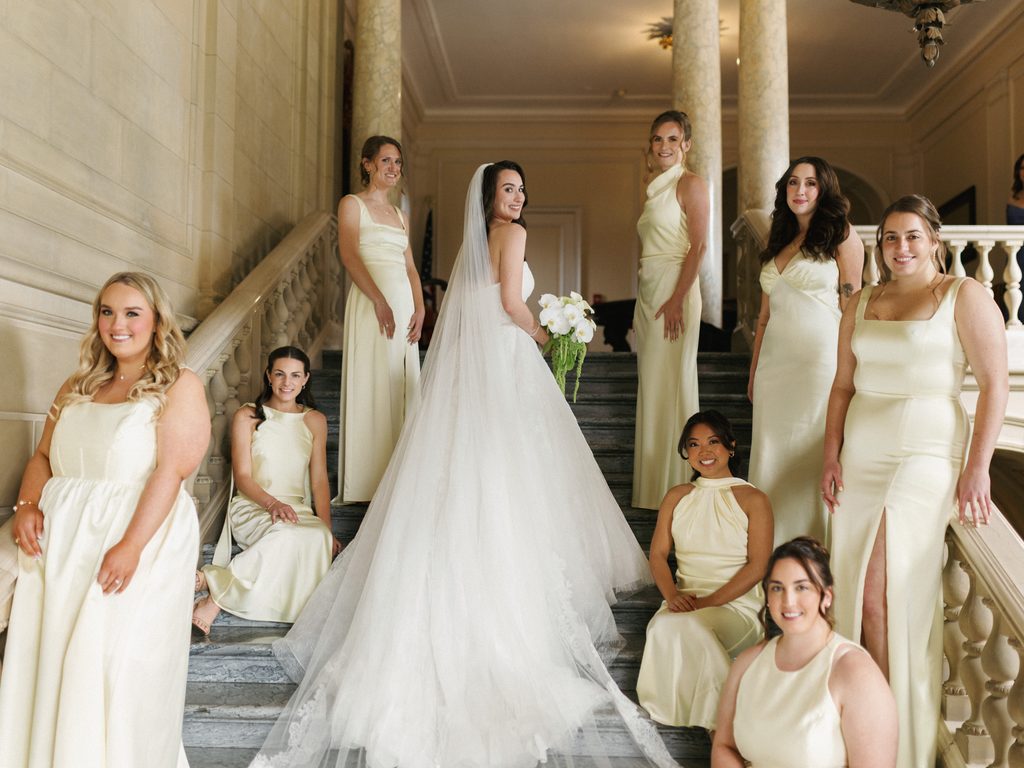 Luxury bridal party inspiration showcasing a bride in a long veil surrounded by bridesmaids wearing sophisticated pastel cream satin dresses