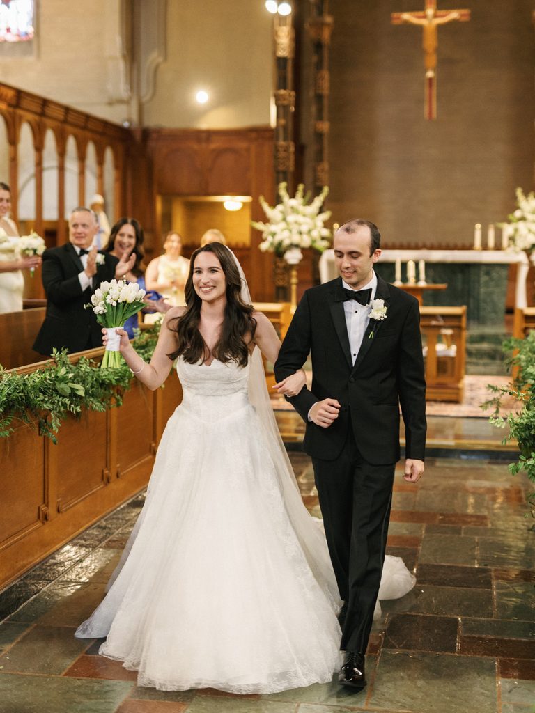 Luxury bride and groom recessional exit featuring a happy couple holding hands and a classic white calla lily wedding bouquet