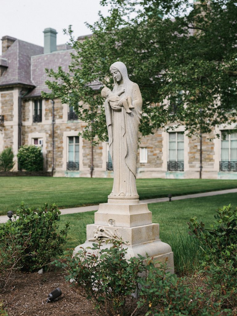 Historic Aldrich Mansion wedding venue exterior showcasing a beautiful stone statue of the Virgin Mary on a manicured green lawn