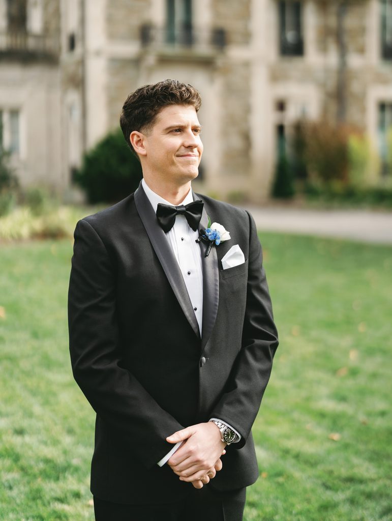Handsome groom posing outdoors during an Aldrich Mansion wedding celebration on a lush green lawn