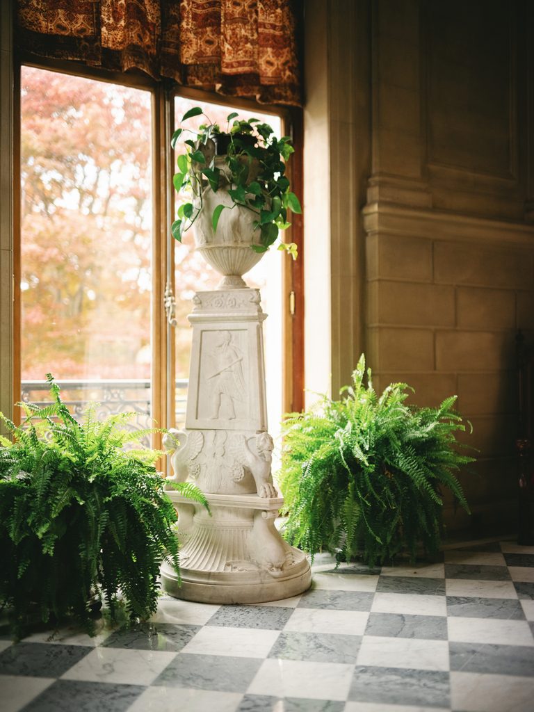 Classic indoor greenery decor during an Aldrich Mansion wedding reception featuring bright ferns on a checkered marble floor