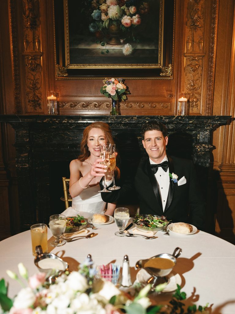 Intimate Aldrich Mansion wedding sweetheart table reception dinner capturing the bride and groom raising a champagne toast